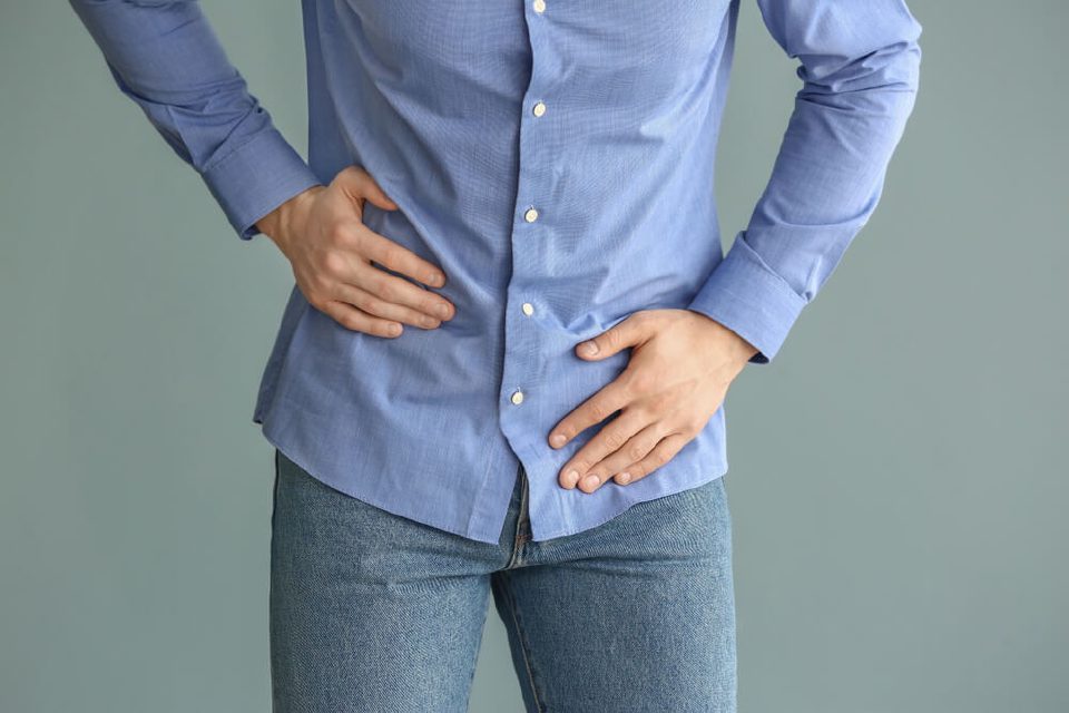 Man holding his lower abdomen, a common area of discomfort with an enlarged prostate