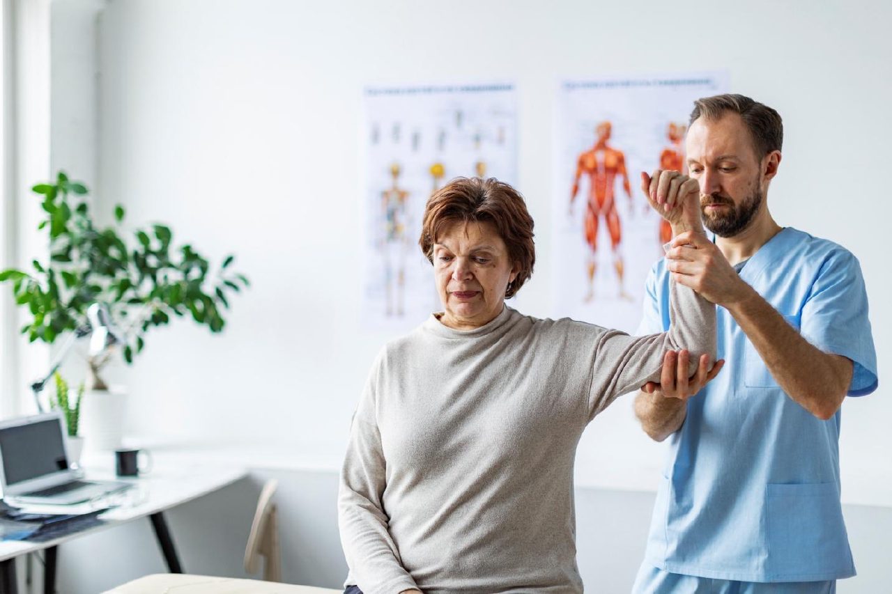 Clinician assessing a patient's elbow movement for chronic elbow pain
